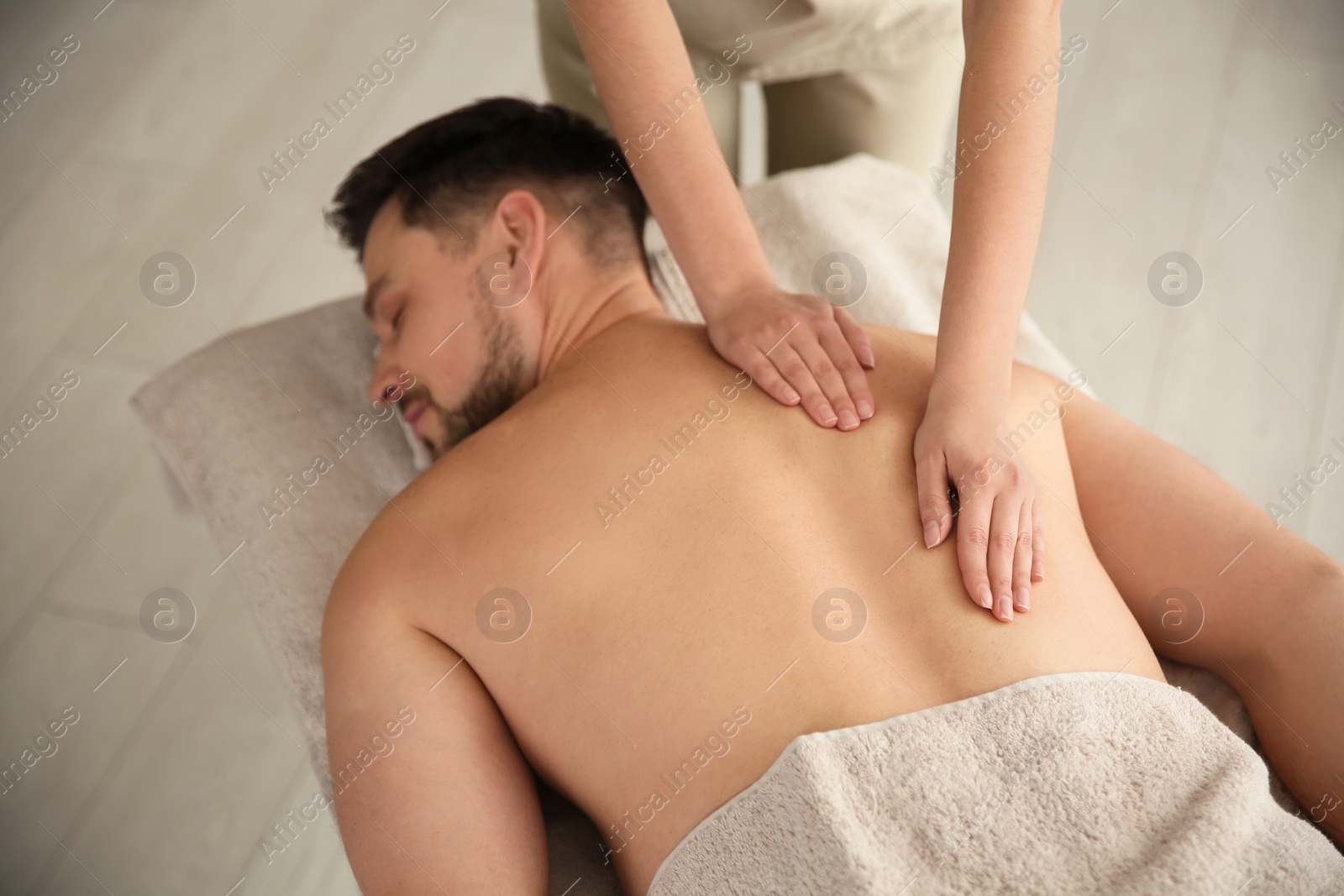 Photo of Handsome man receiving back massage in spa salon
