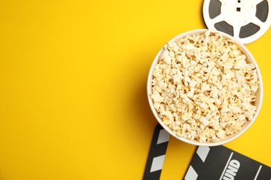 Photo of Flat lay composition with popcorn, film reel and clapperboard on color background