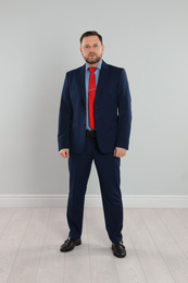 Full length portrait of mature man near light grey wall