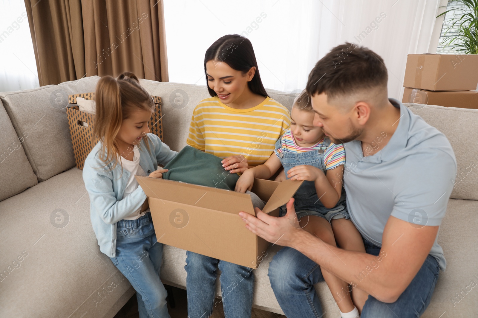 Photo of Happy family unpacking moving box at their new house