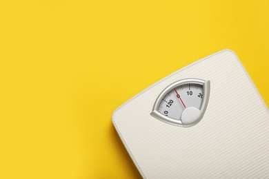 Photo of Weigh scales on yellow background, top view with space for text. Overweight concept
