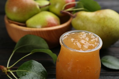 Photo of Delicious pear jam and fresh fruits on dark background, closeup