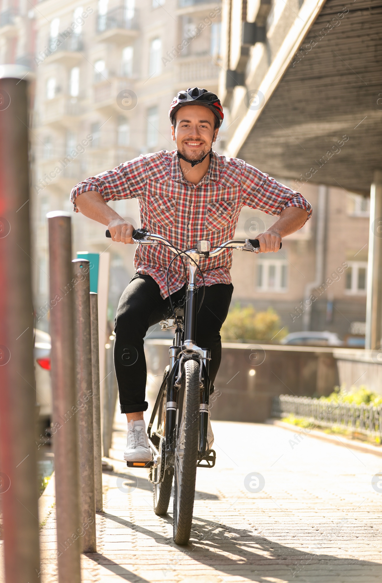Photo of Handsome happy man in helmet riding bicycle on city street