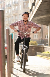Handsome happy man in helmet riding bicycle on city street
