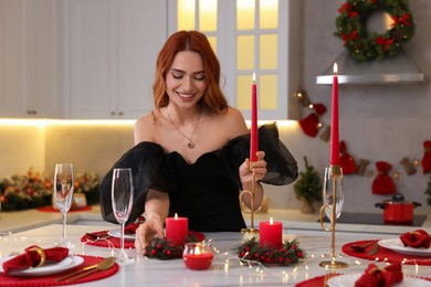 Photo of Beautiful young woman setting table for Christmas celebration in kitchen