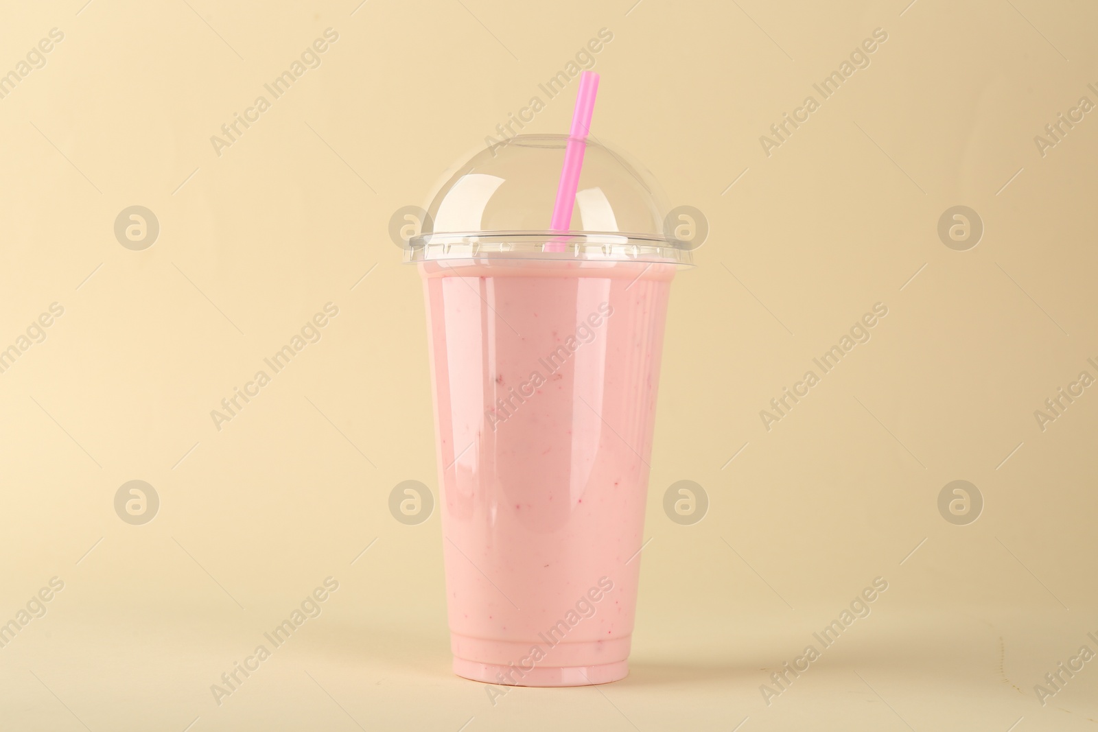 Photo of Plastic cup of tasty smoothie on beige background