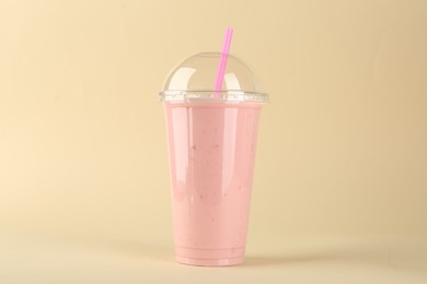 Photo of Plastic cup of tasty smoothie on beige background