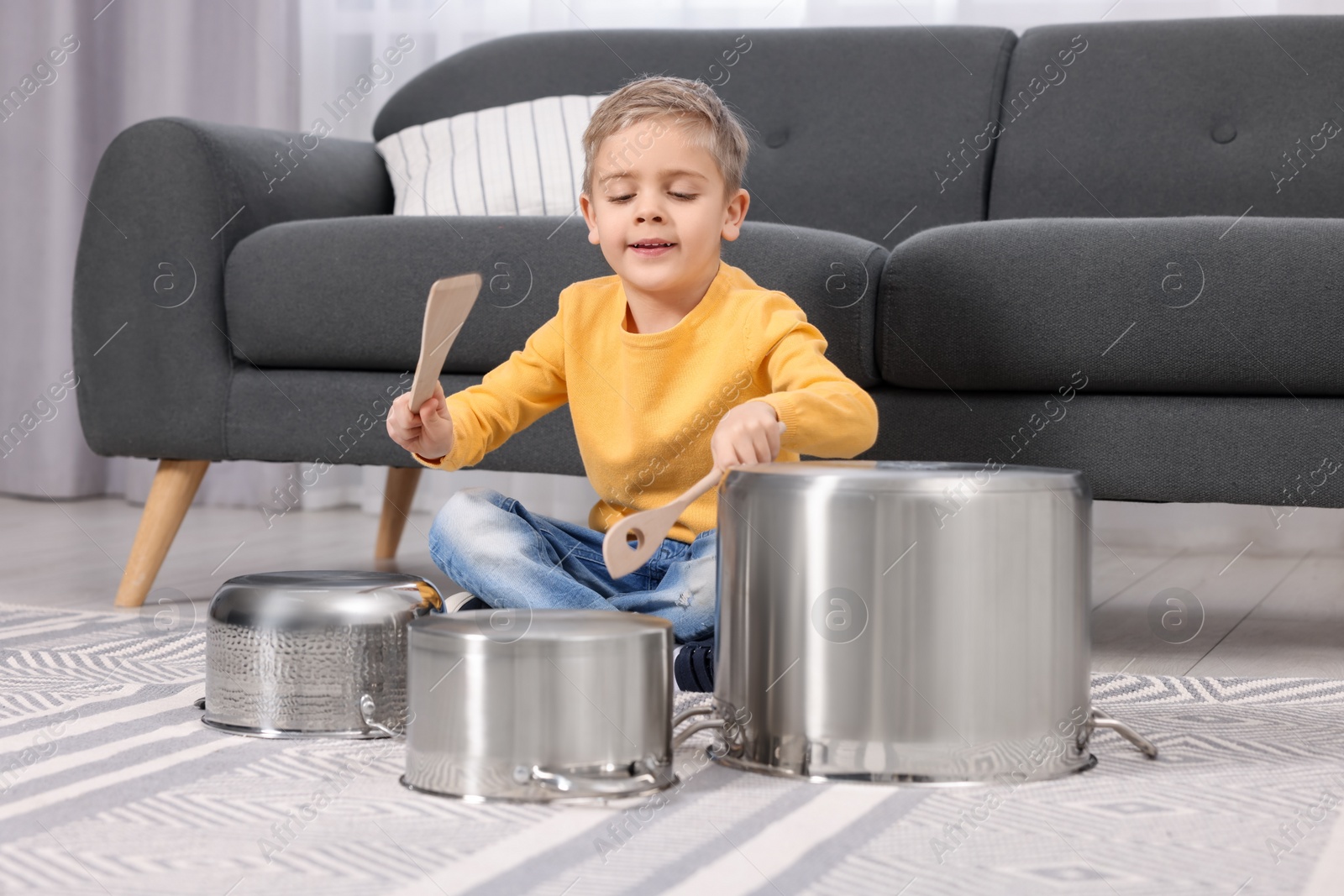 Photo of Little boy pretending to play drums on pots at home