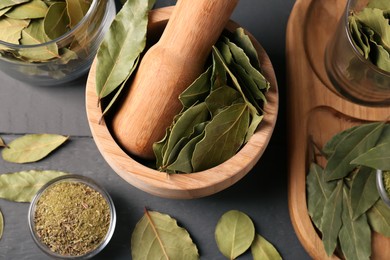 Photo of Whole and ground bay leaves on grey wooden table, view from above
