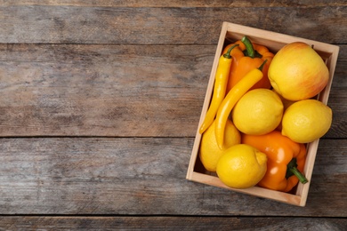 Crate full of fresh ripe fruits and vegetables on wooden background, top view. Space for text