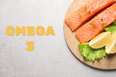 Image of Omega 3. Board with fresh cut salmon, microgreens, lemon and lettuce on light table, top view