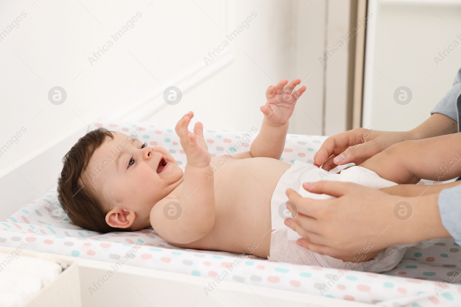 Photo of Mother changing baby's diaper on table at home, closeup