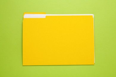 Photo of Yellow file with documents on light green background, top view