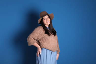 Beautiful overweight woman posing on blue background. Plus size model