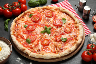 Photo of Delicious pizza Margherita and ingredients on dark grey table