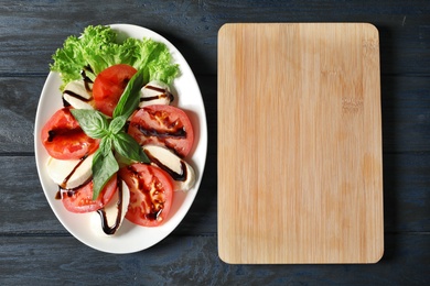 Photo of Plate with delicious fresh salad and wooden board on table, top view