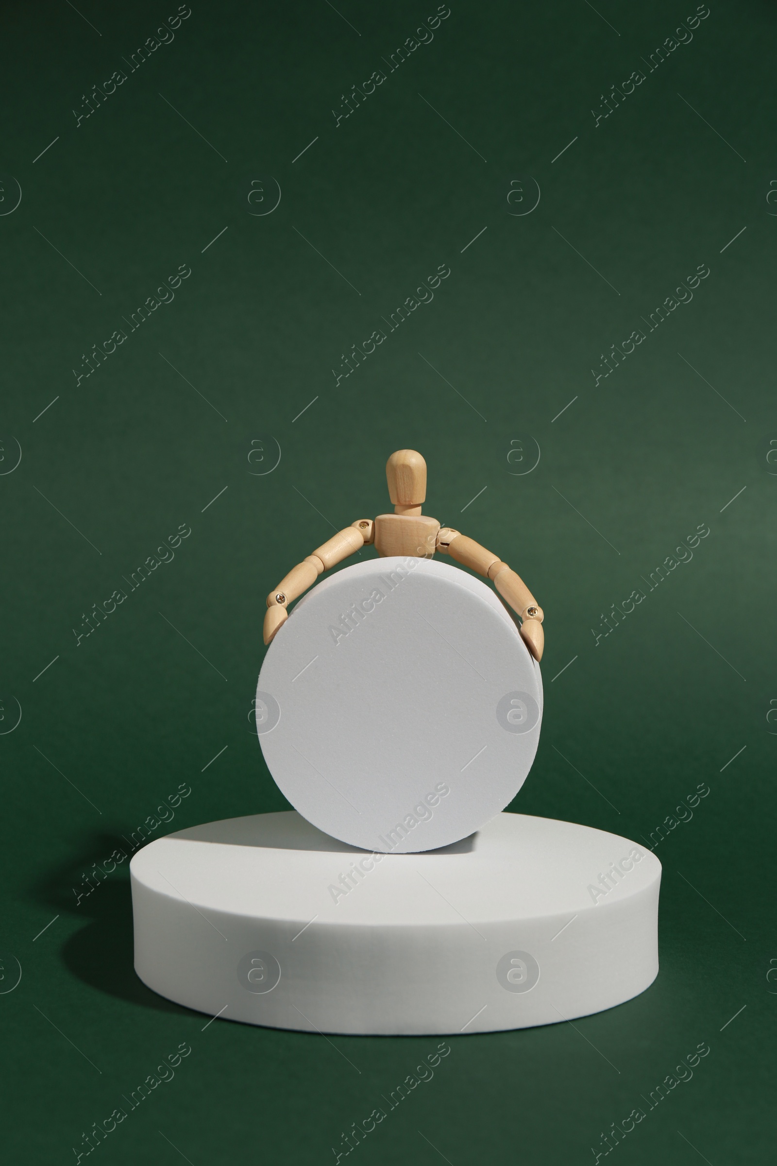 Photo of Product photography props. Round shaped podiums and wooden mannequin on green background