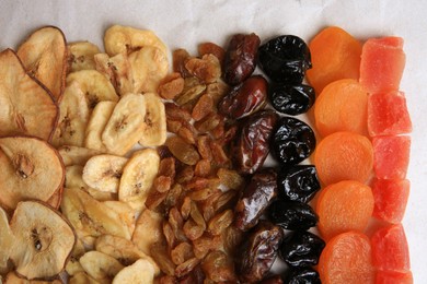 Different tasty dried fruits on paper, flat lay