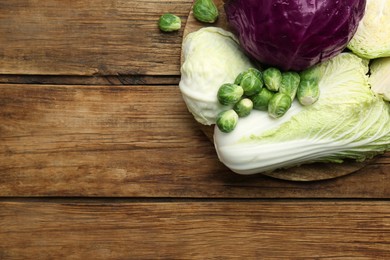 Photo of Different types of cabbage on wooden table, flat lay. Space for text