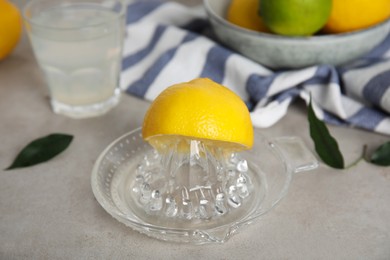 Photo of Glass squeezer with lemon and juice on light table, closeup