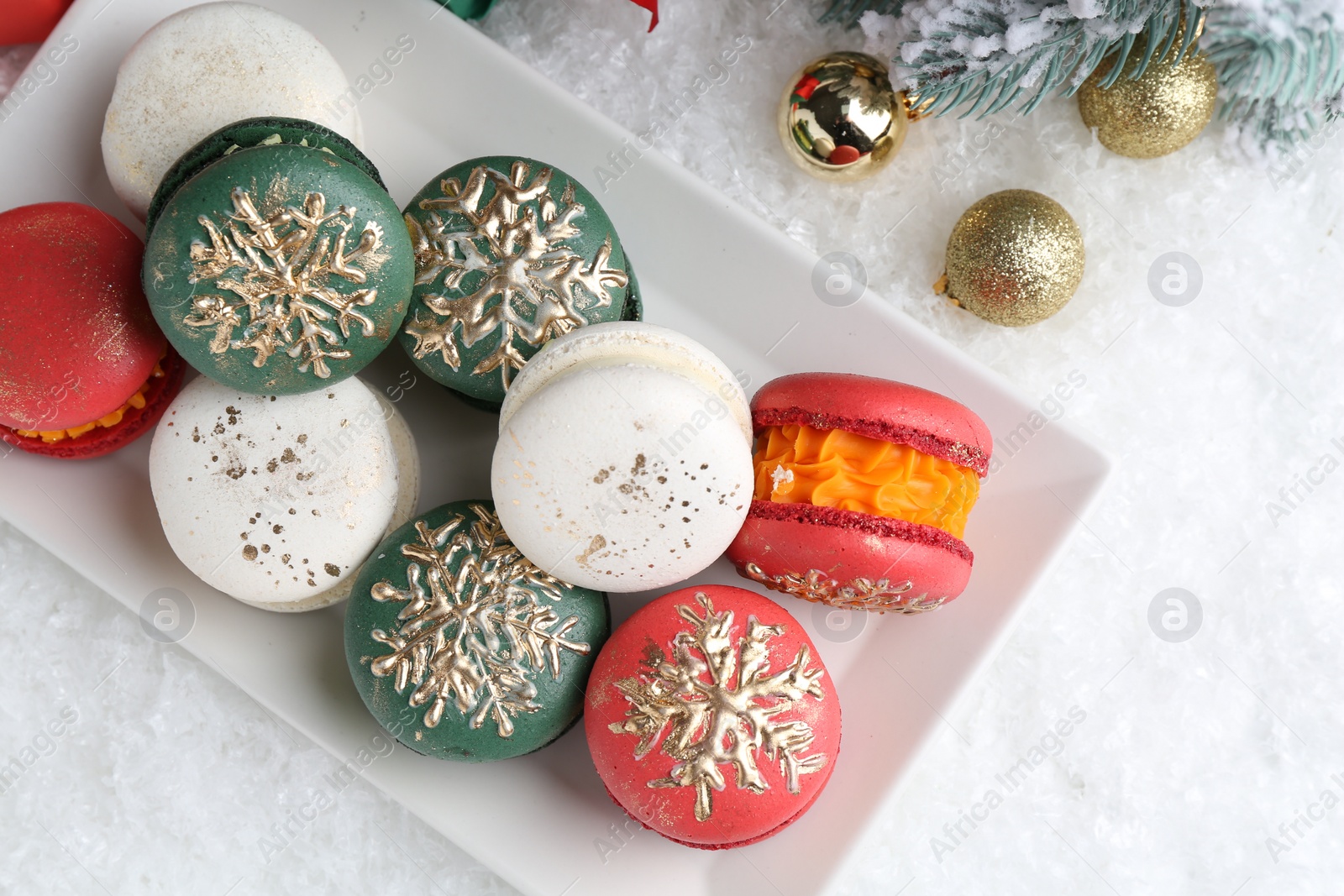 Photo of Beautifully decorated Christmas macarons and festive decor on snow, flat lay