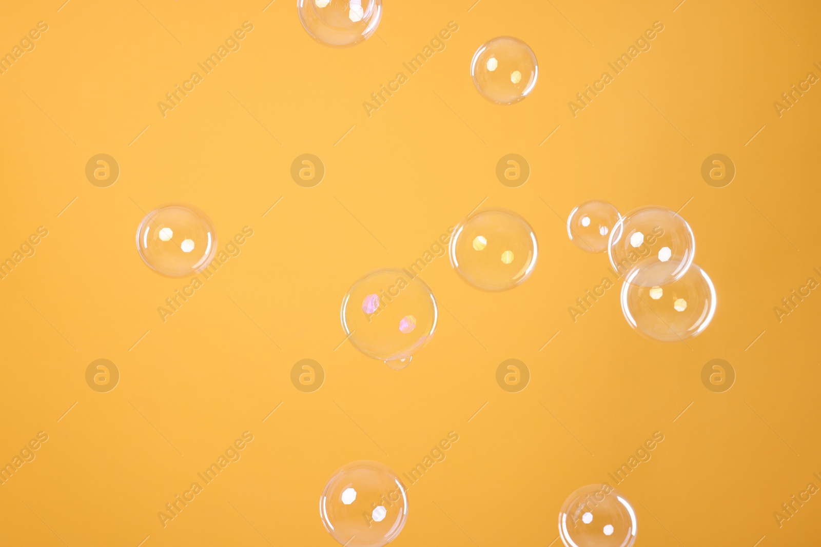 Photo of Many beautiful soap bubbles on orange background