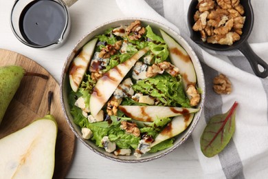 Delicious pear salad with sauce in bowl on light table, flat lay