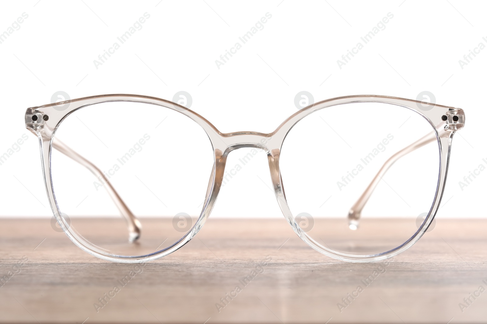 Photo of Stylish glasses with transparent frame on wooden table against white background