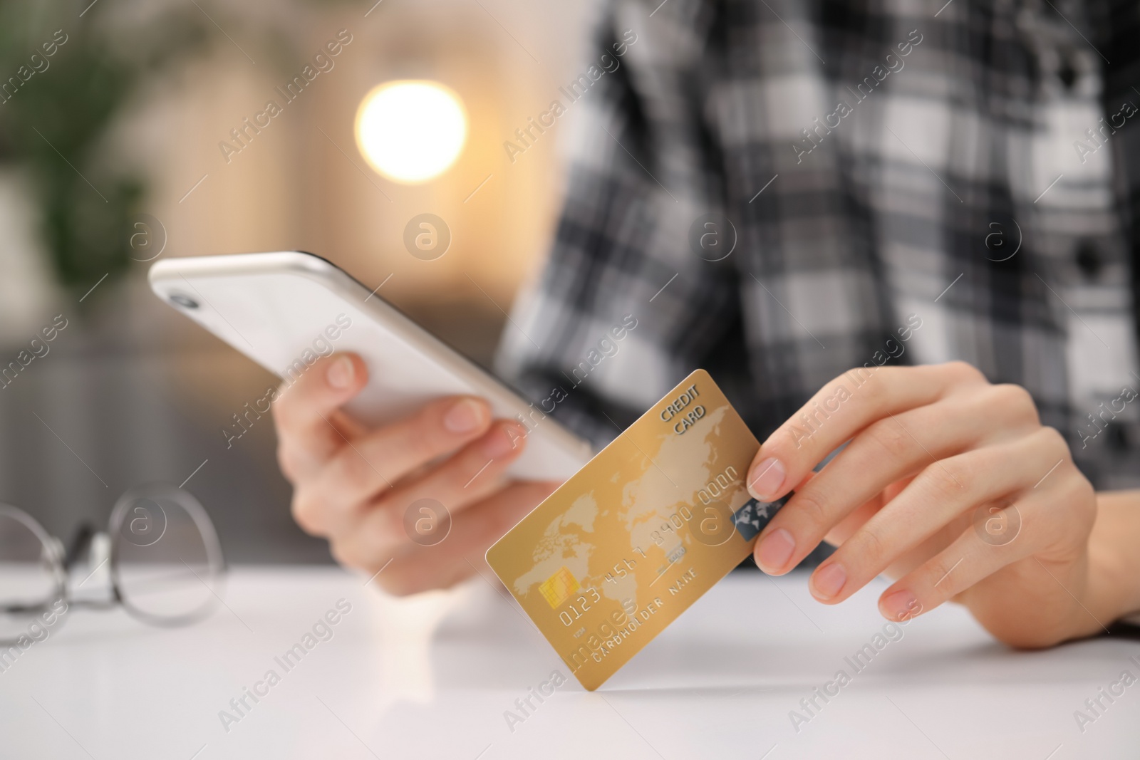 Photo of Woman with credit card using smartphone for online shopping at white table, closeup