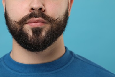 Man with mustache on light blue background, closeup