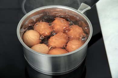 Boiling chicken eggs in saucepan on electric stove