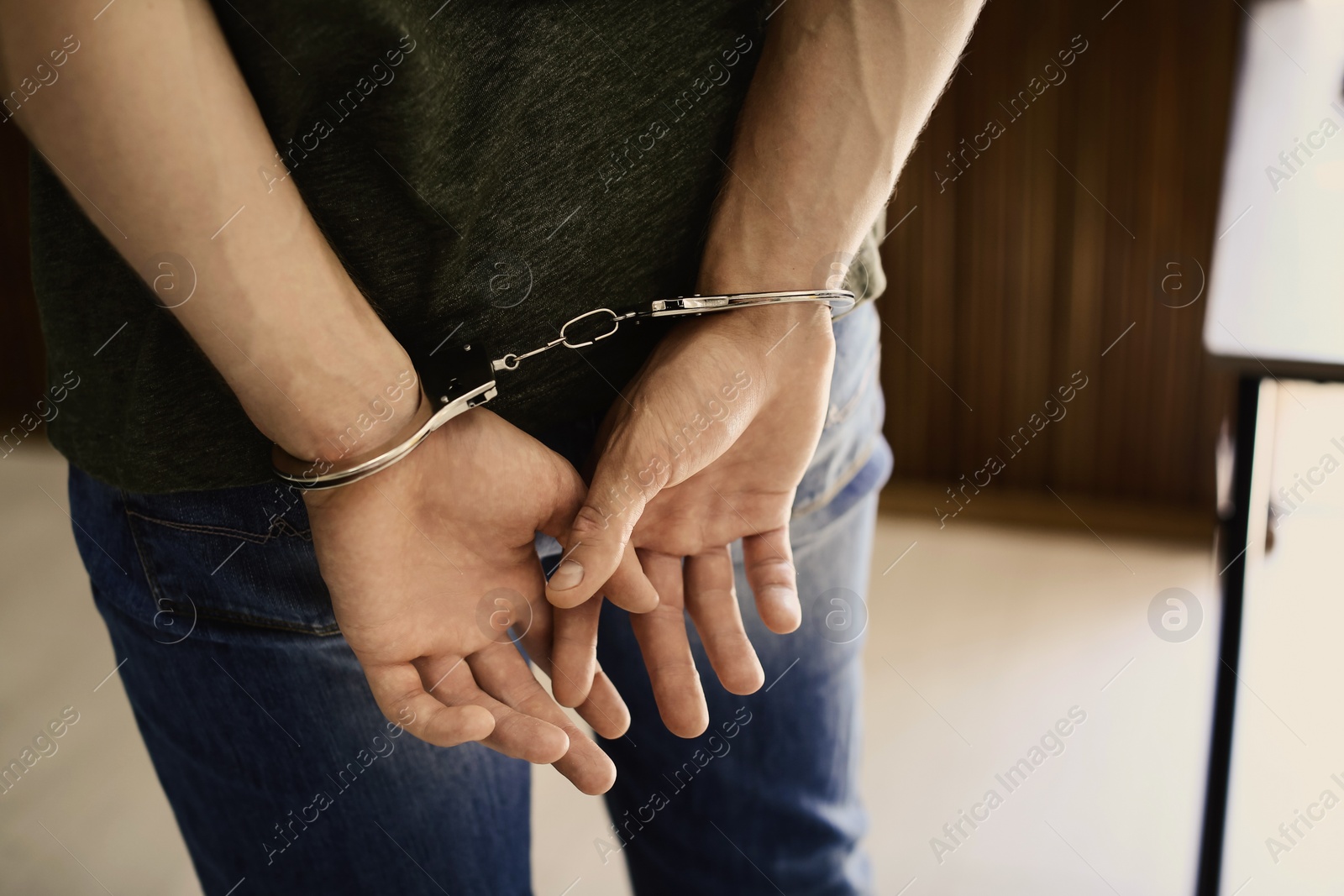 Photo of Man detained in handcuffs indoors, closeup view. Criminal law