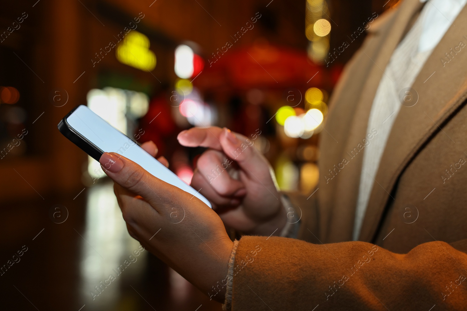 Photo of Woman using smartphone on night city street, closeup