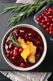Photo of Fresh cranberry sauce, rosemary, orange peel and berries on table, top view