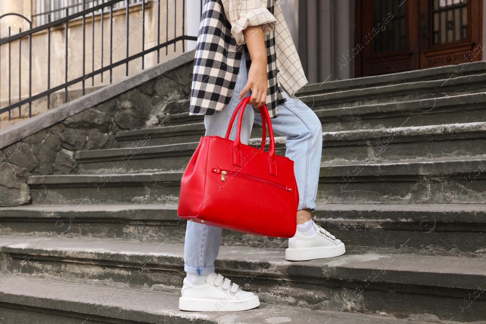 Photo of Young woman with stylish bag on stairs outdoors, closeup