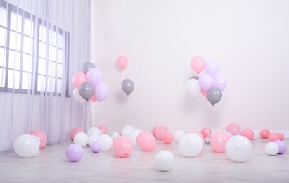 Room decorated with colorful balloons near wall