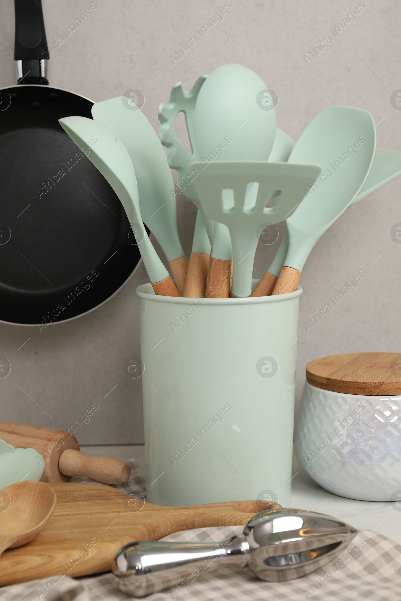 Photo of Set of different kitchen utensils on table near gray wall