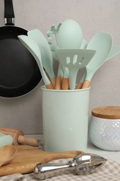 Set of different kitchen utensils on table near gray wall