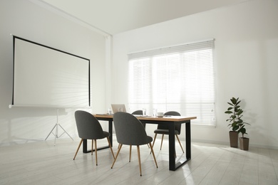 Conference room interior with wooden table and video projection screen