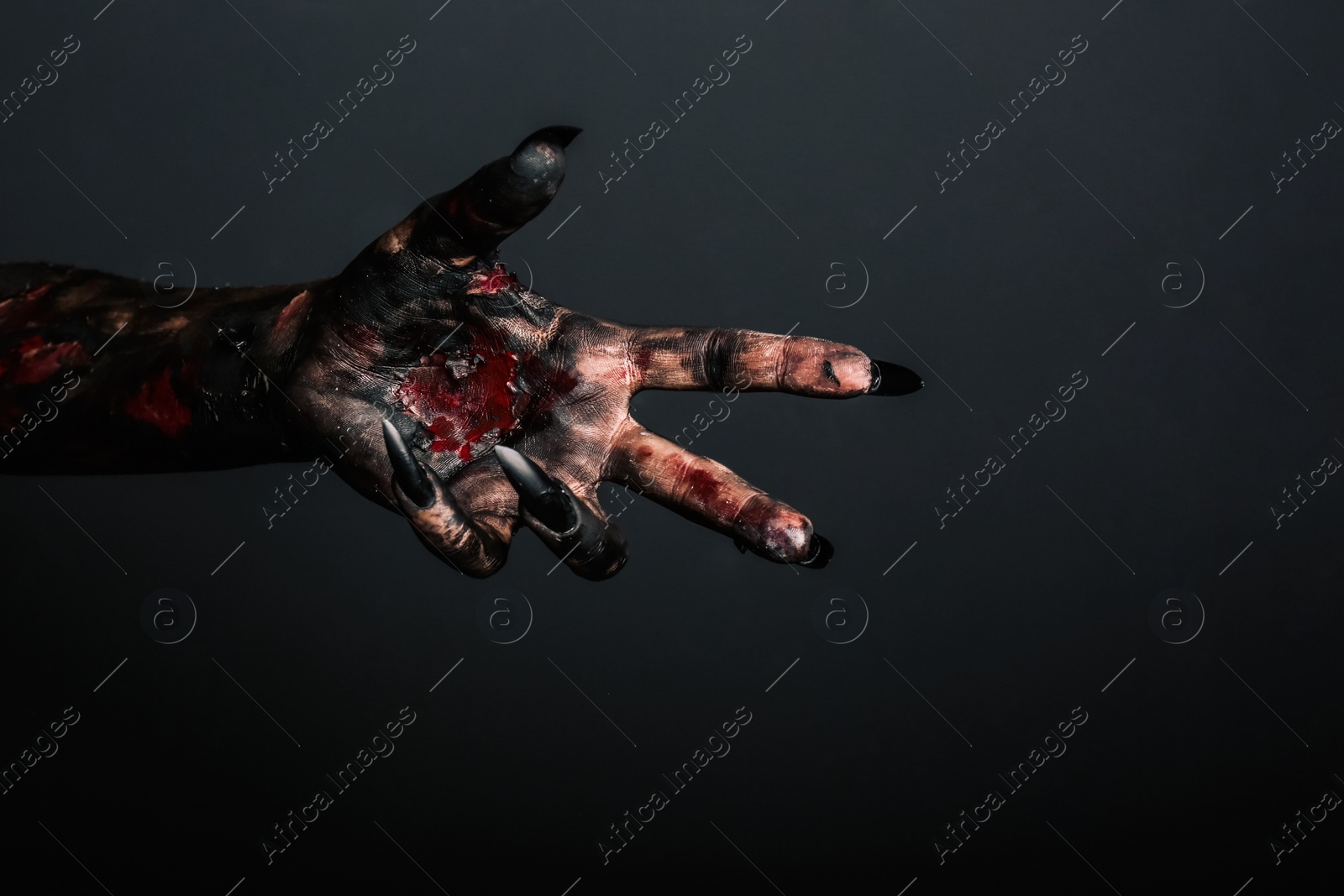 Photo of Scary monster on black background, closeup of hand. Halloween character