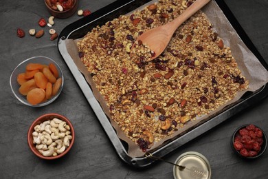 Photo of Tray with tasty granola, nuts and dry fruits on black table, flat lay
