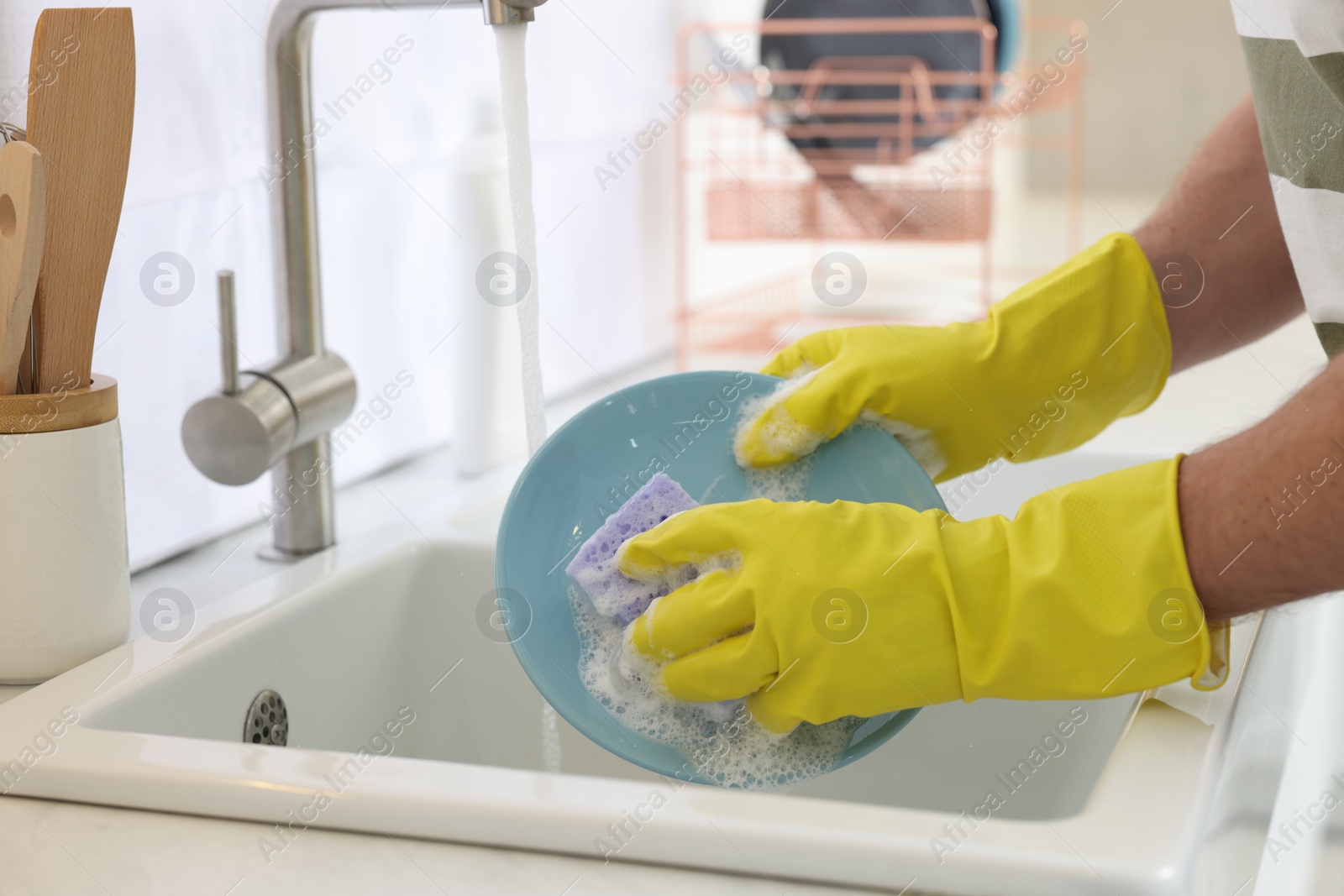 Photo of Man washing plate above sink in kitchen, closeup