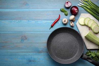 Photo of Flat lay composition with frying pan and fresh products on light blue wooden table, space for text