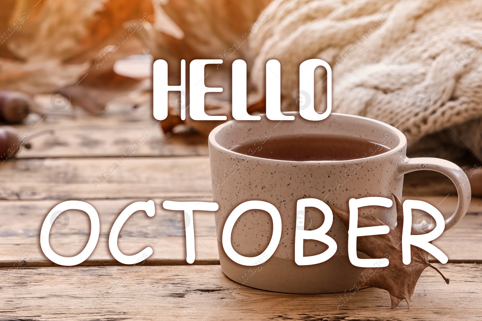 Image of Hello October card. Cup of hot drink and autumn leaves on wooden table