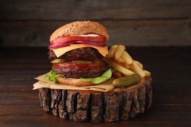 Photo of Tasty cheeseburger with patties, French fries and pickle on wooden table