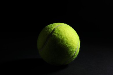Photo of One bright tennis ball on black background