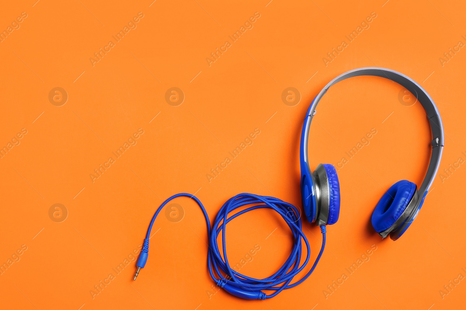 Photo of Stylish headphones on color background, top view. Space for text