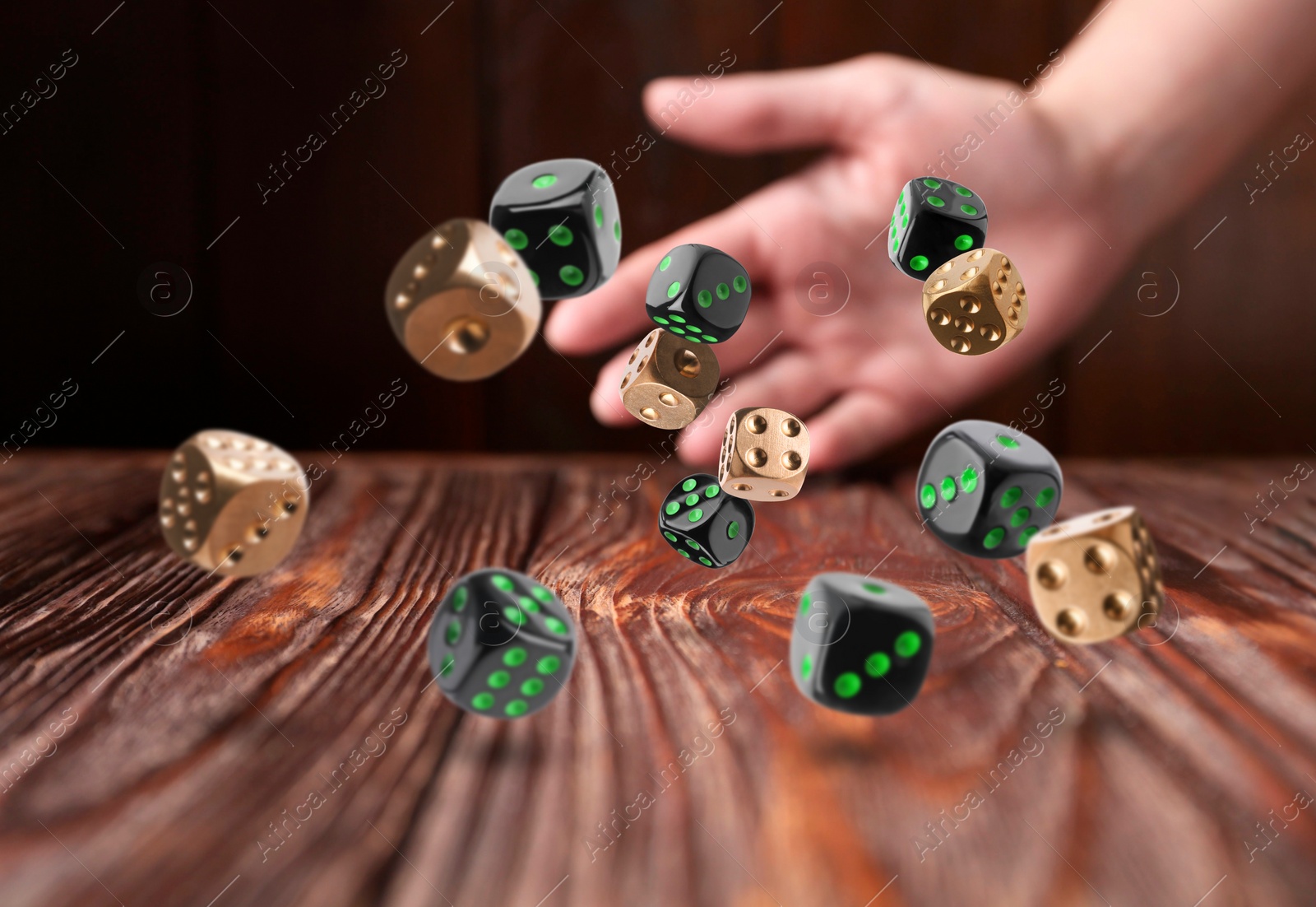 Image of Woman throwing many dice on wooden table, closeup