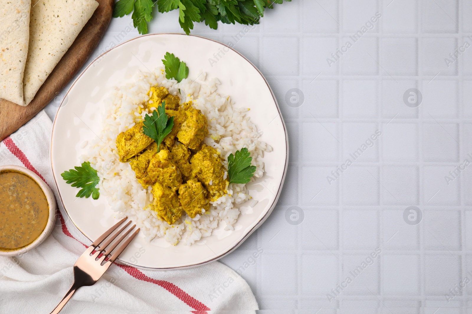 Photo of Delicious rice and chicken with curry sauce on white tiled table, flat lay. Space for text