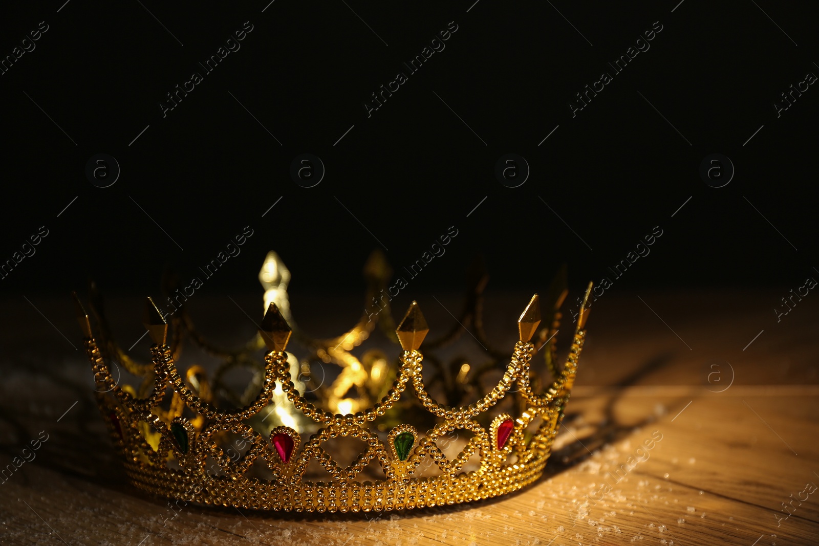 Photo of Beautiful golden crown with gems on wooden table. Fantasy item